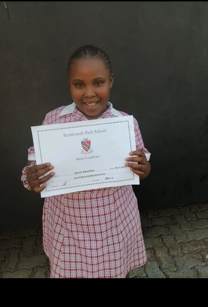 Naledi Magopane holding her Rembrandt Park School Merit Certificate
