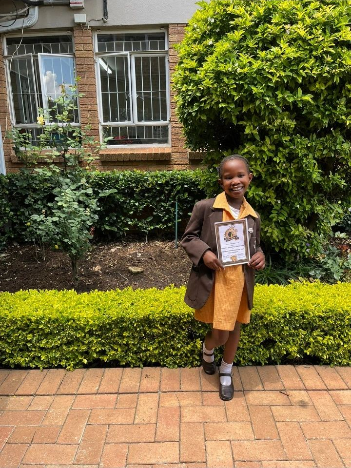 Scholar in school uniform proudly holding a school certificate